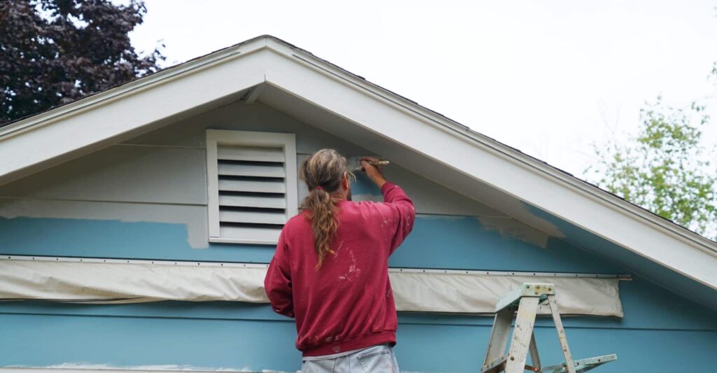 man painting the house siding